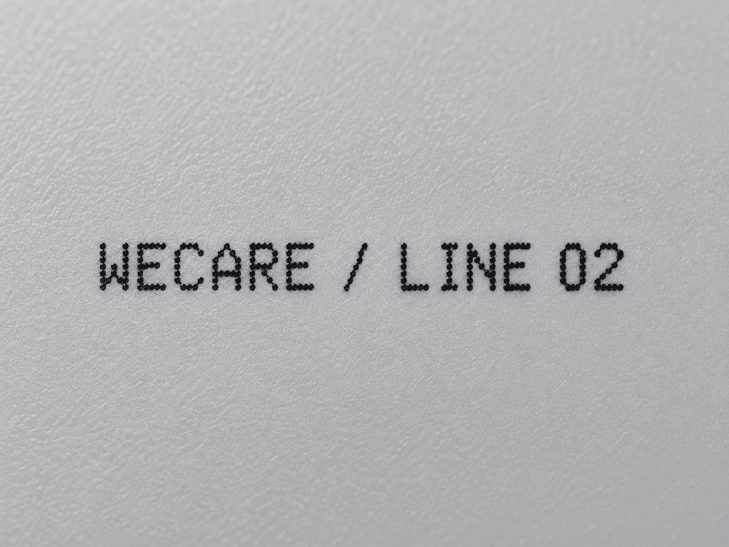 Close-up WECARE line identification text printed on industrial polymer